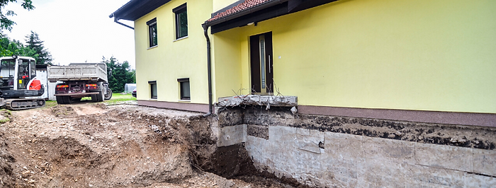 Foundation exposed under a yellow home.