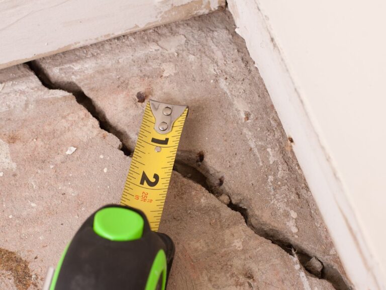 A tape measure spanning a concrete crack.