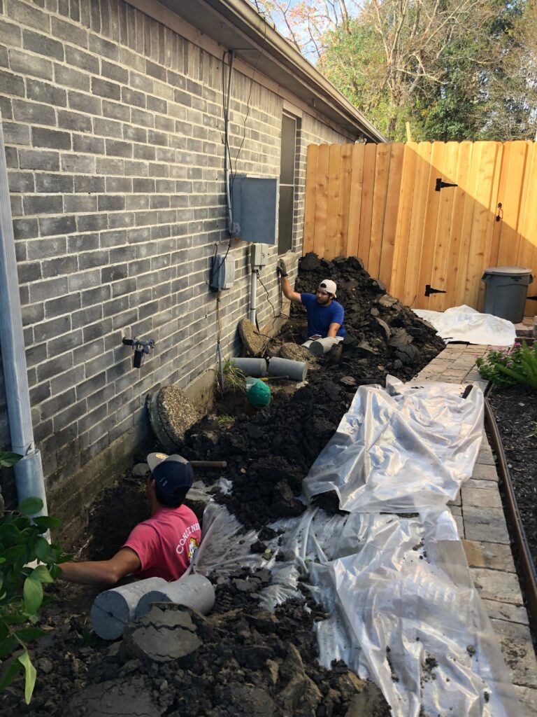 Two workers of Continental Foundation Restoration working on foundation repair for a house.