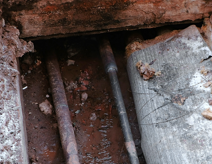 Pipes exposed underneath a foundation.